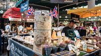 Borough Market food stalls with cheese, flowers, bread and more, and traders ready to welcome customers.