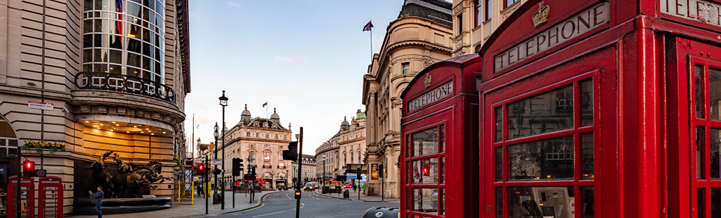 A closeup of two red telephone boxes and Piccadilly Circus in the background