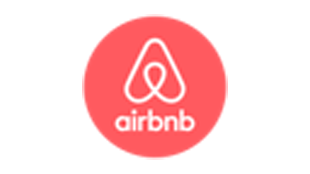 A red circular logo with a white triangle in the centre on top of text that reads airbnb in white font.